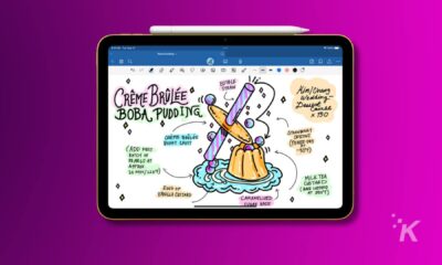 apple ipad with an apple pencil laid on top of it hovering over a purple background