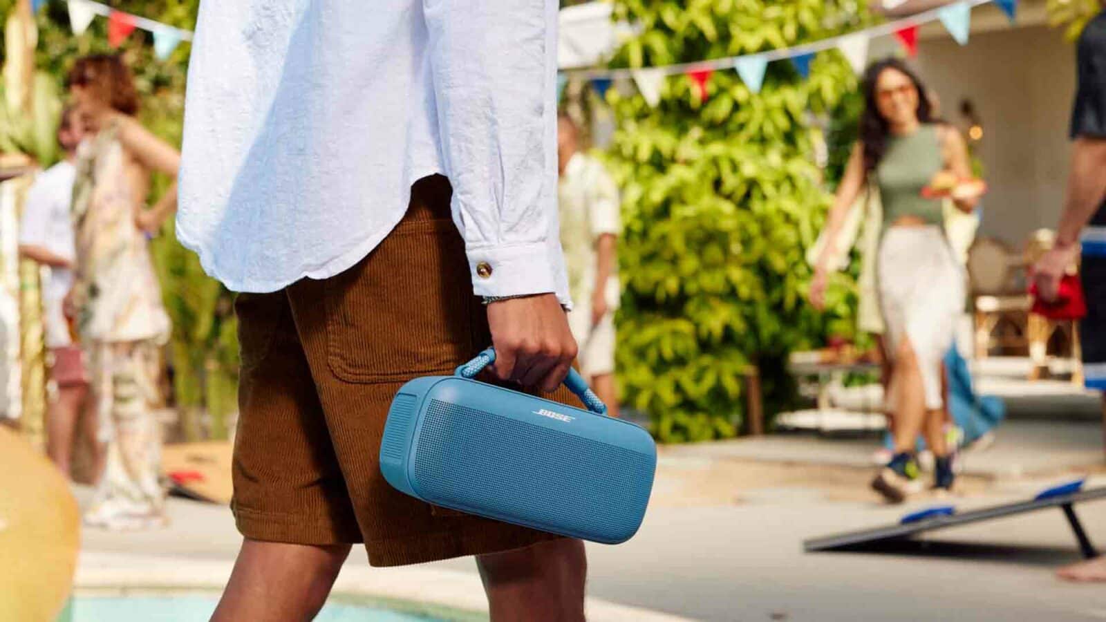 Person carrying portable speaker at pool party.