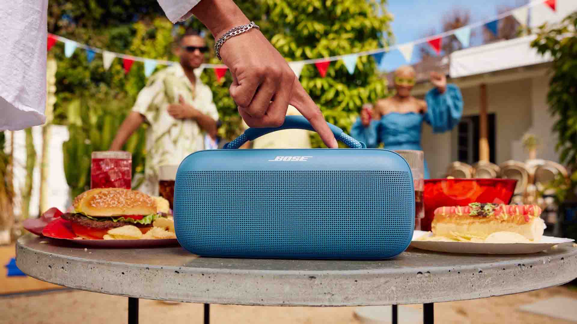 Person adjusting portable speaker at outdoor party.