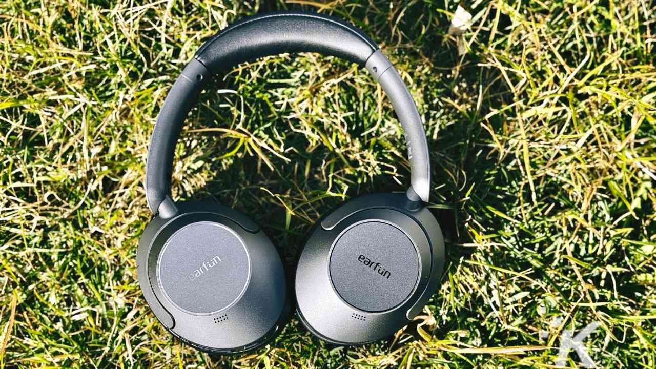 Black over-ear headphones on a grassy surface.