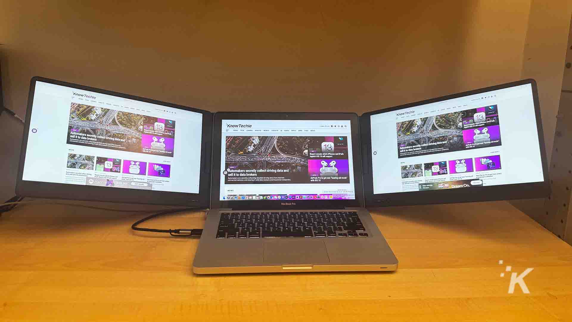 the QQH triple laptop screen extender with a laptop on a desk.