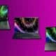 Three laptops with colorful screen savers on purple background.