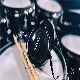 A drummer is playing a tom-tom drum, a membranophone percussion instrument, indoors with AUDEZE headphones.