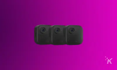 Three black Blink security cameras in a horizontal line on a purple background.