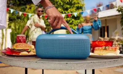 Person adjusting portable speaker at outdoor party.