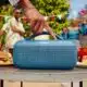 Person adjusting portable speaker at outdoor party.