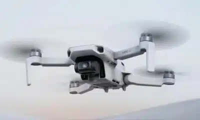 White mini 4K camera drone flying, soft background
