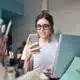 Freelancer looking at phone while working on laptop.