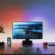 computer monitor on a desk with contrasting colored lighting on the wall behind