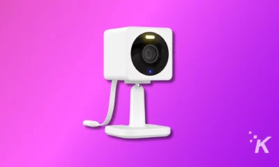 This is a stylized graphic of a white web camera with a prominent lens, mounted on a stand, against a vibrant purple background.