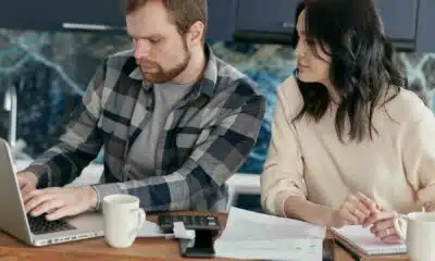 Two professionals collaborating on a laptop at office desk.