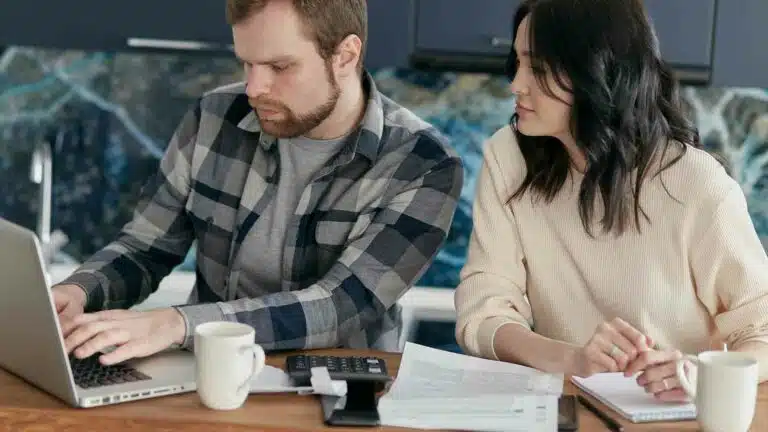 Two professionals collaborating on a laptop at office desk.