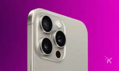 Close-up of a modern smartphone's triple camera system on a silver backing, with a purple background.