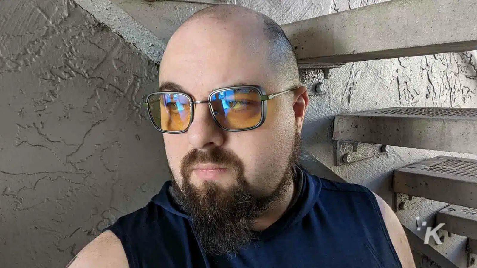 Man with sunglasses near concrete stairs.