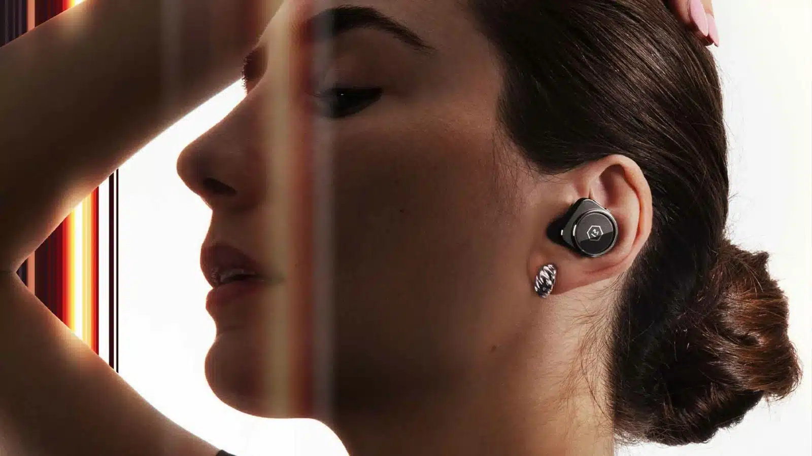 A woman holding her head wearing M&D earbuds