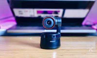 obsbot tiny 4k webcam sitting on a desk in front of half opened laptop