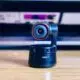 obsbot tiny 4k webcam sitting on a desk in front of half opened laptop
