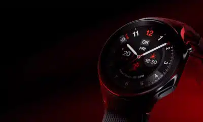 A smartwatch with a black interface displaying time, date, heart rate, and steps, set against a dark red background.