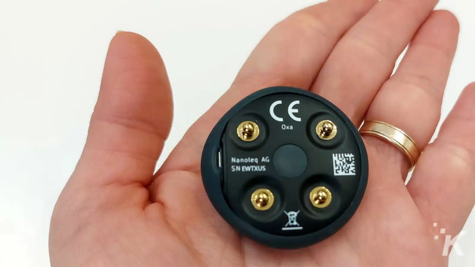 Hand holding small electronic device with CE mark.