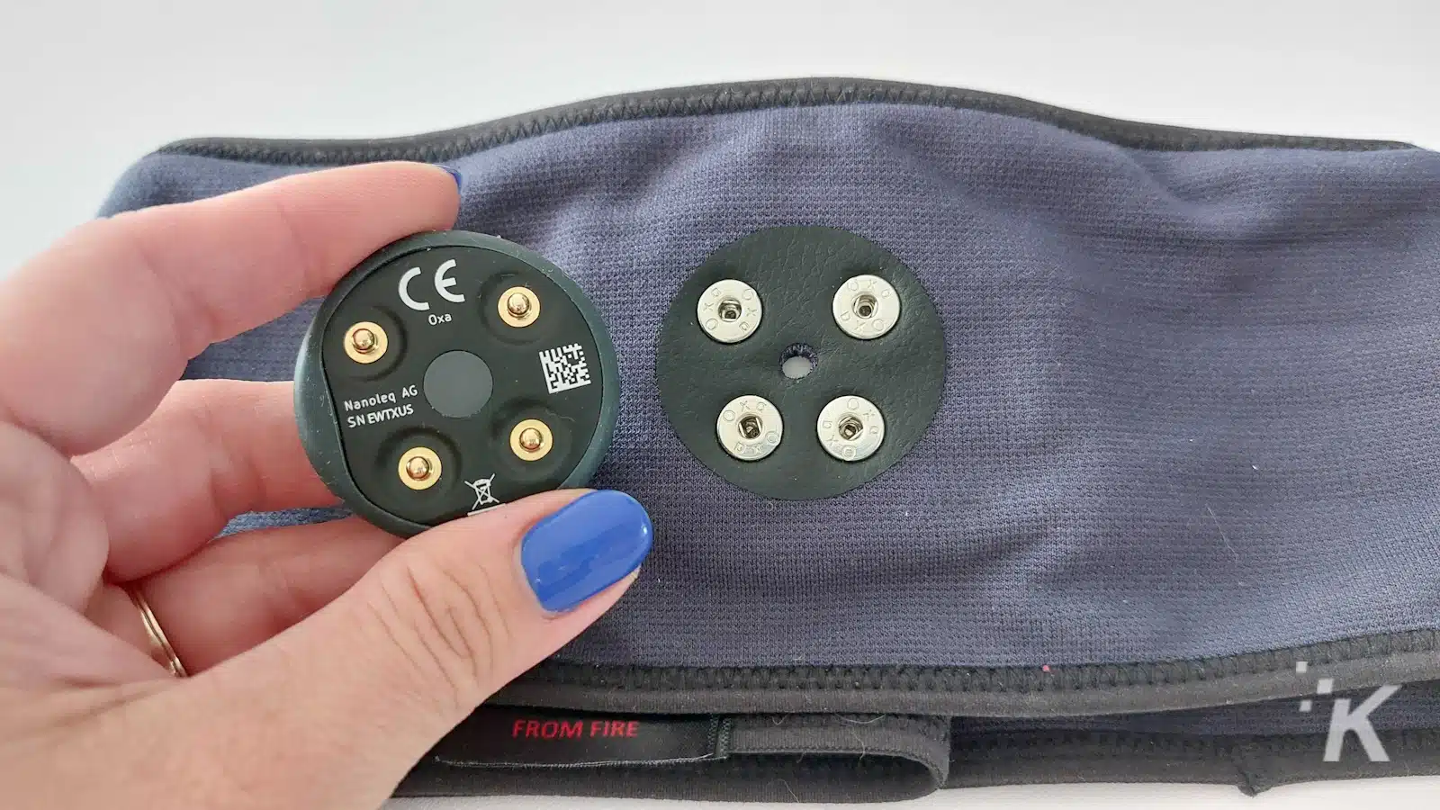 Hand holding electronic component on textile surface.