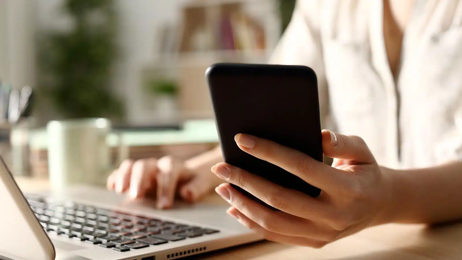 Person on phone in front of a laptop