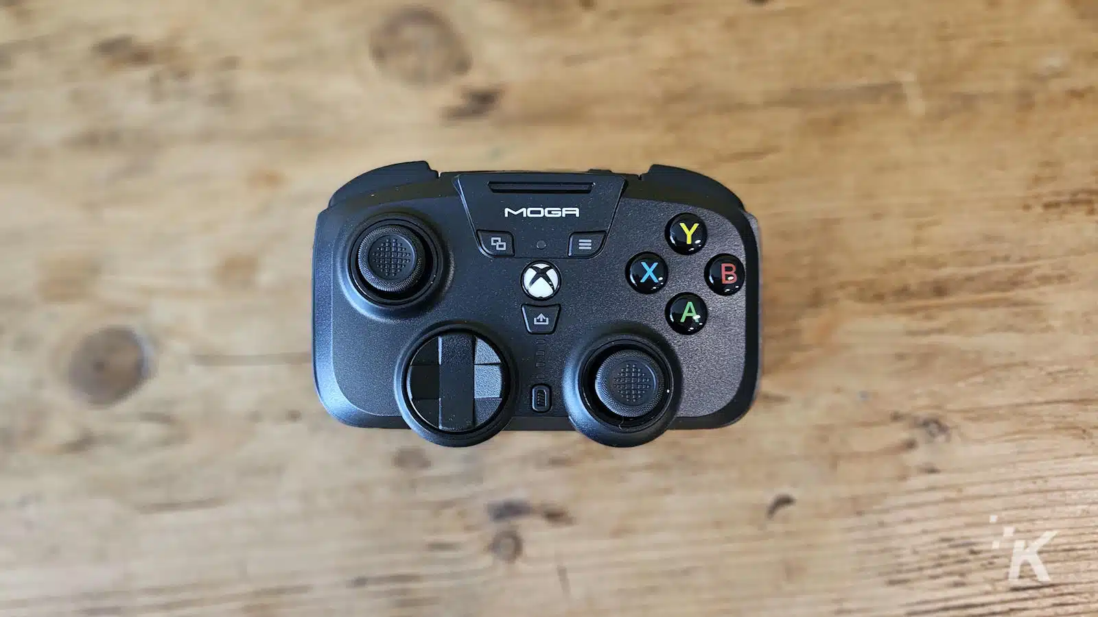 MOGA Xbox game controller on wooden surface.