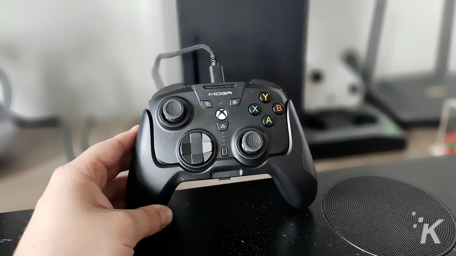 Hand holding a MOGA Xbox controller indoors.