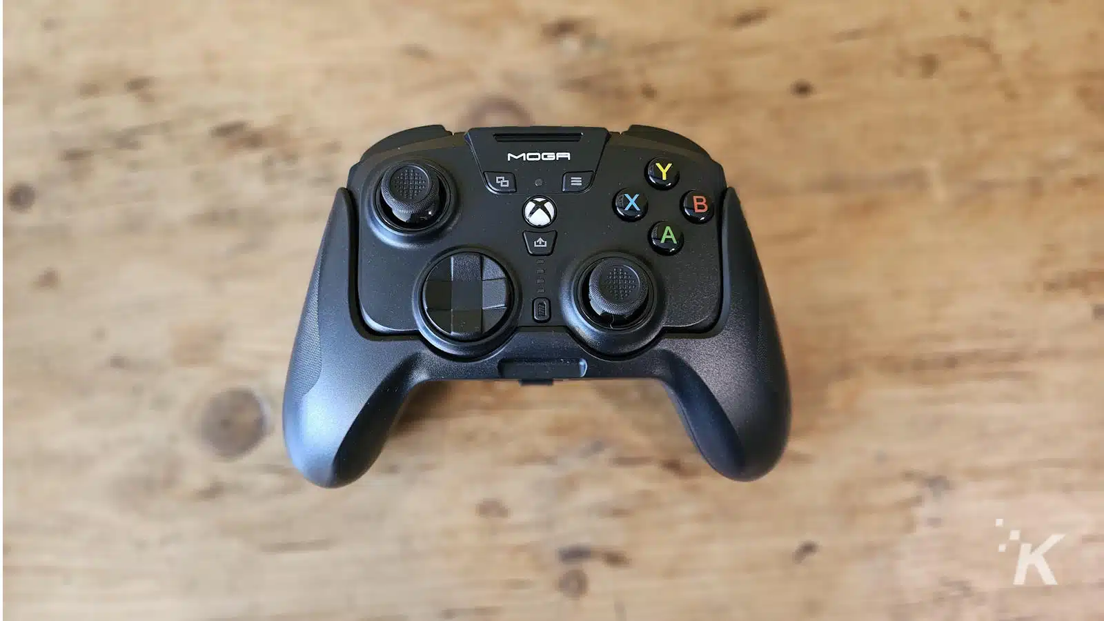Xbox MOGA gaming controller on wooden table.