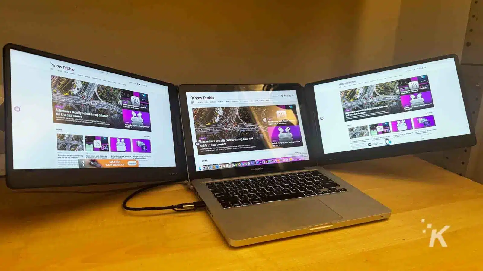 the QQH triple laptop screen extender with a laptop on a desk.