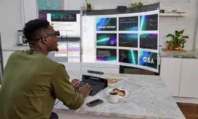 A person sits at a table with a computer and a cup of coffee.