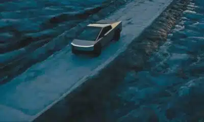 Futuristic truck driving on rugged terrain at dusk.