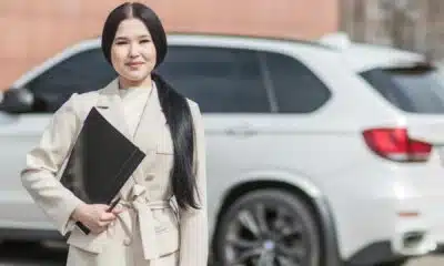 Professional woman with folder beside white car.